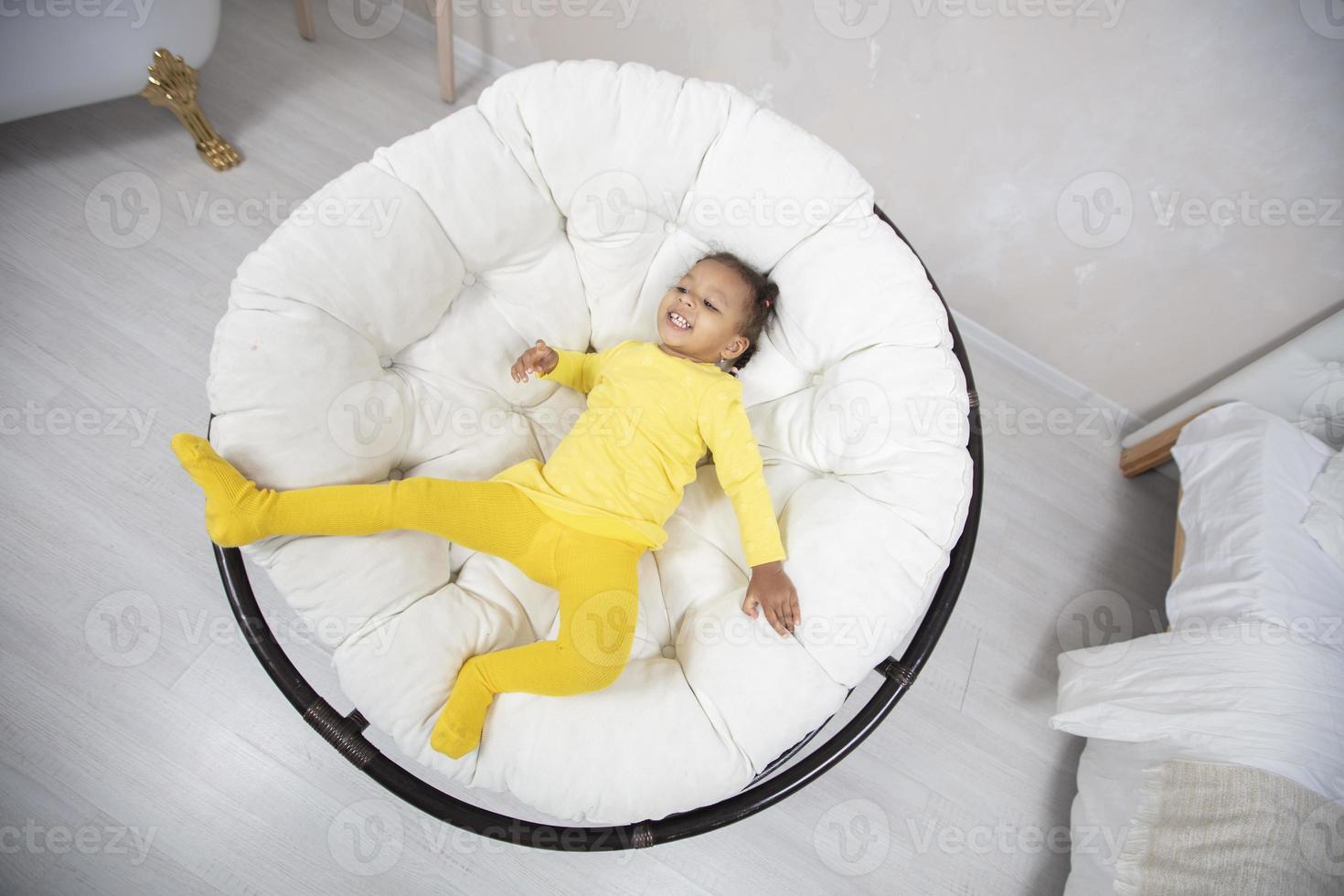 Photographed from above a little African girl in an easy chair. photo