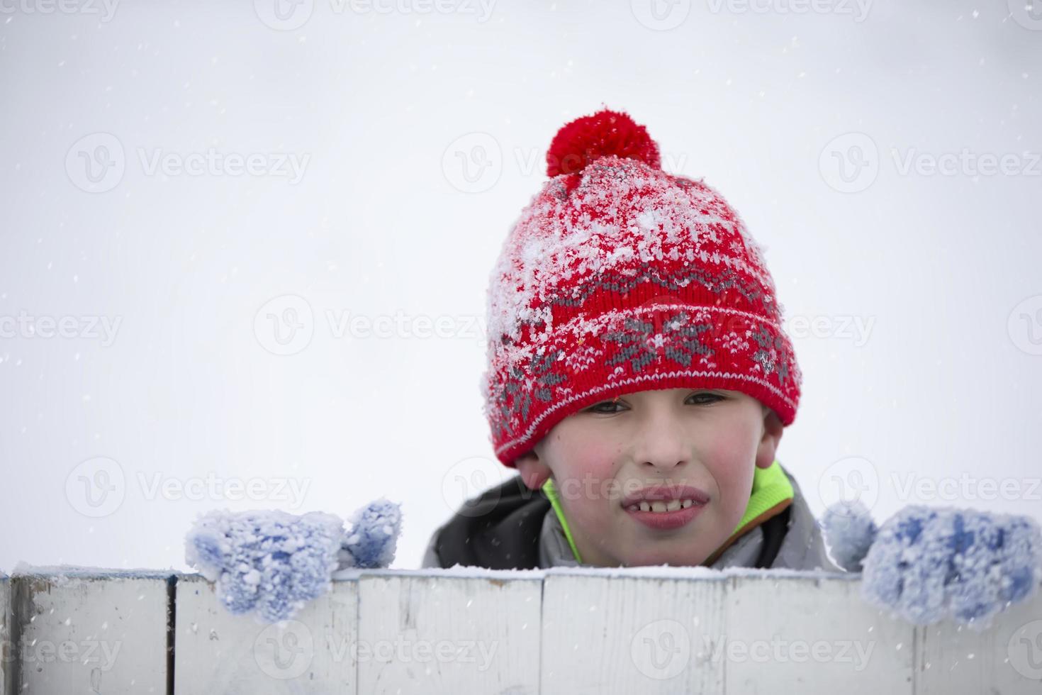 Child in winter. A little boy in a warm hat and mittens looks at the camera and smiles. photo