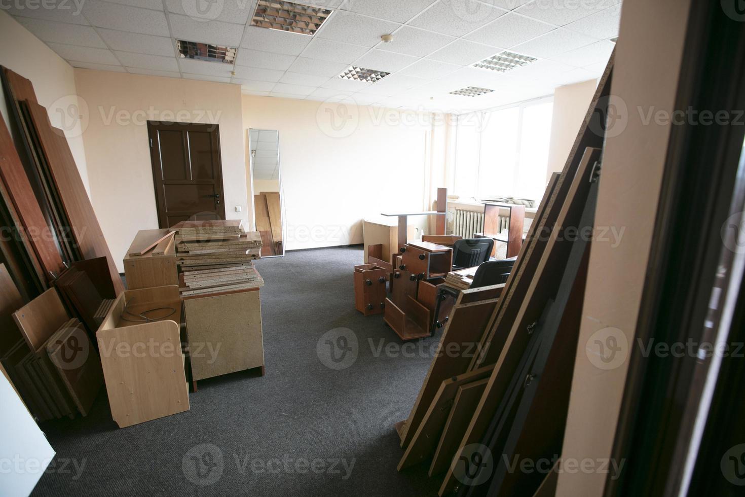 Lots of disassembled and scattered office furniture in an empty room. photo