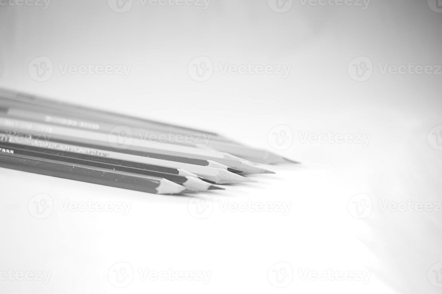 lápices de colores perfectamente alineados sobre papel blanco, hay sacapuntas y hojas foto