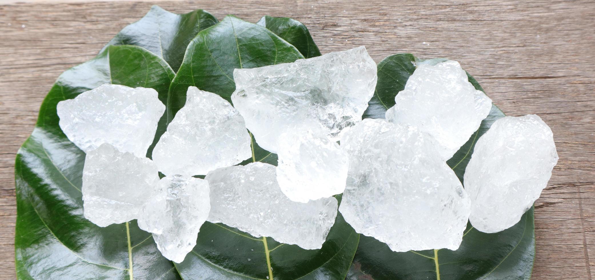 Crystal clear alum cubes or Potassium alum on green leaves chemical compound substance concept for beauty spa and underarm treatment industrial photo