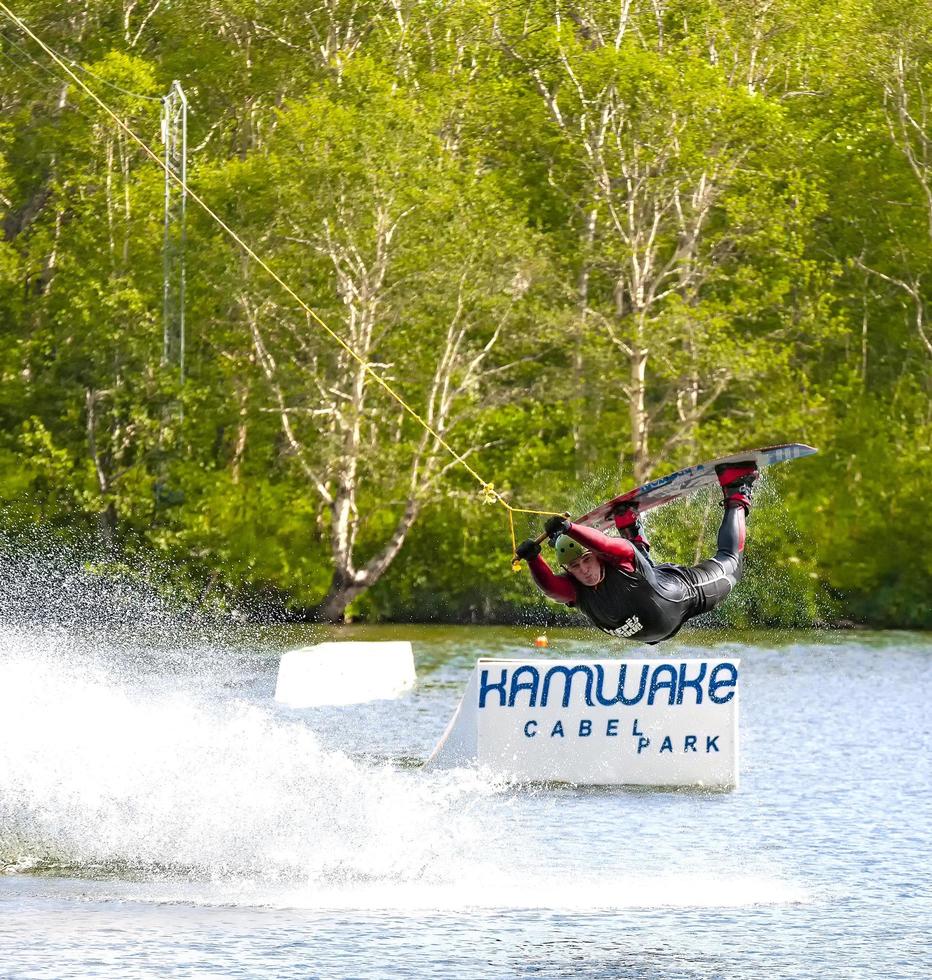 kamchatka, rusia- 10 de junio de 2021 - hombre haciendo wakeboard en el lago en kamchatka detrás del barco foto