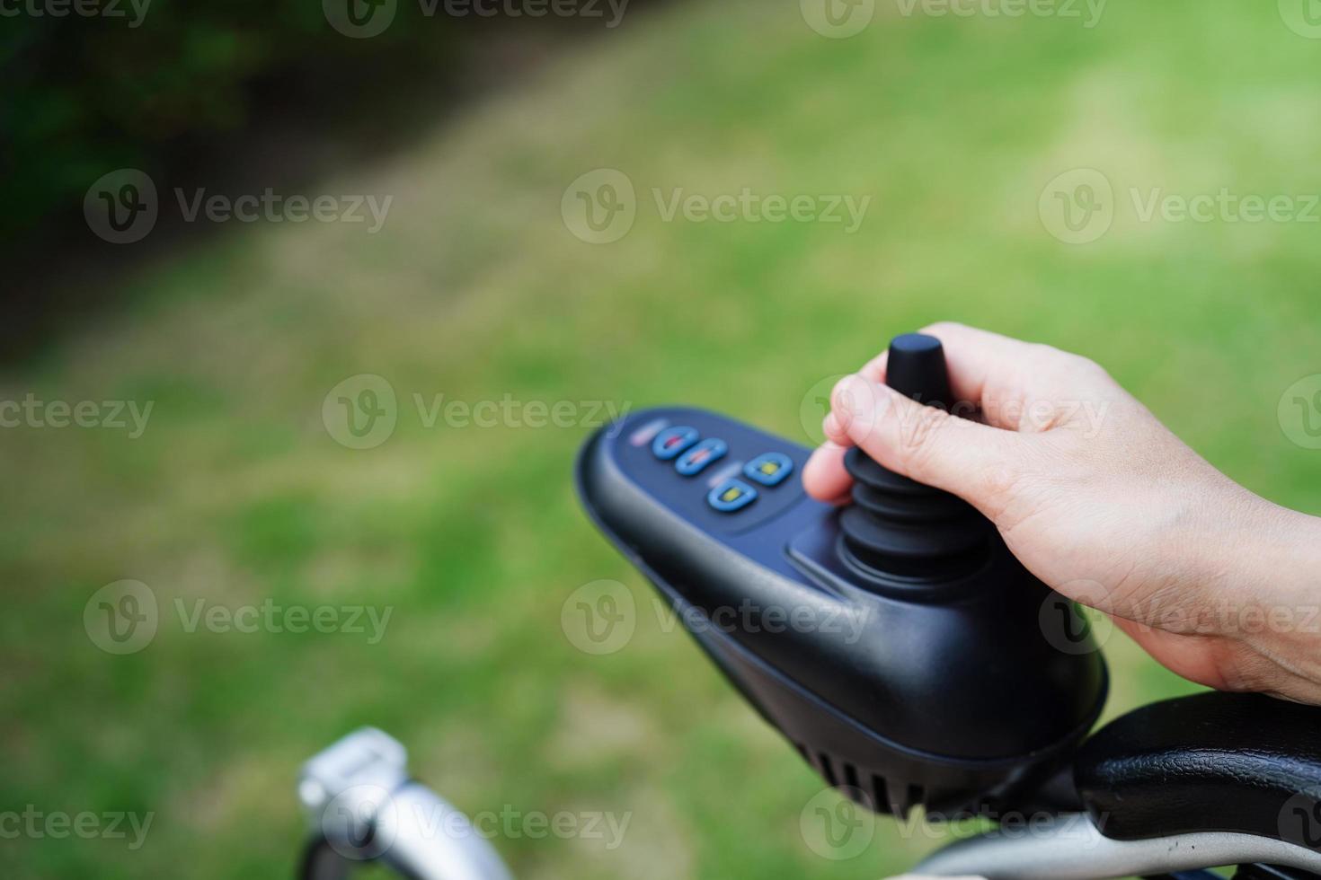 Asian elderly woman disability patient sitting on electric wheelchair in park, medical concept. photo