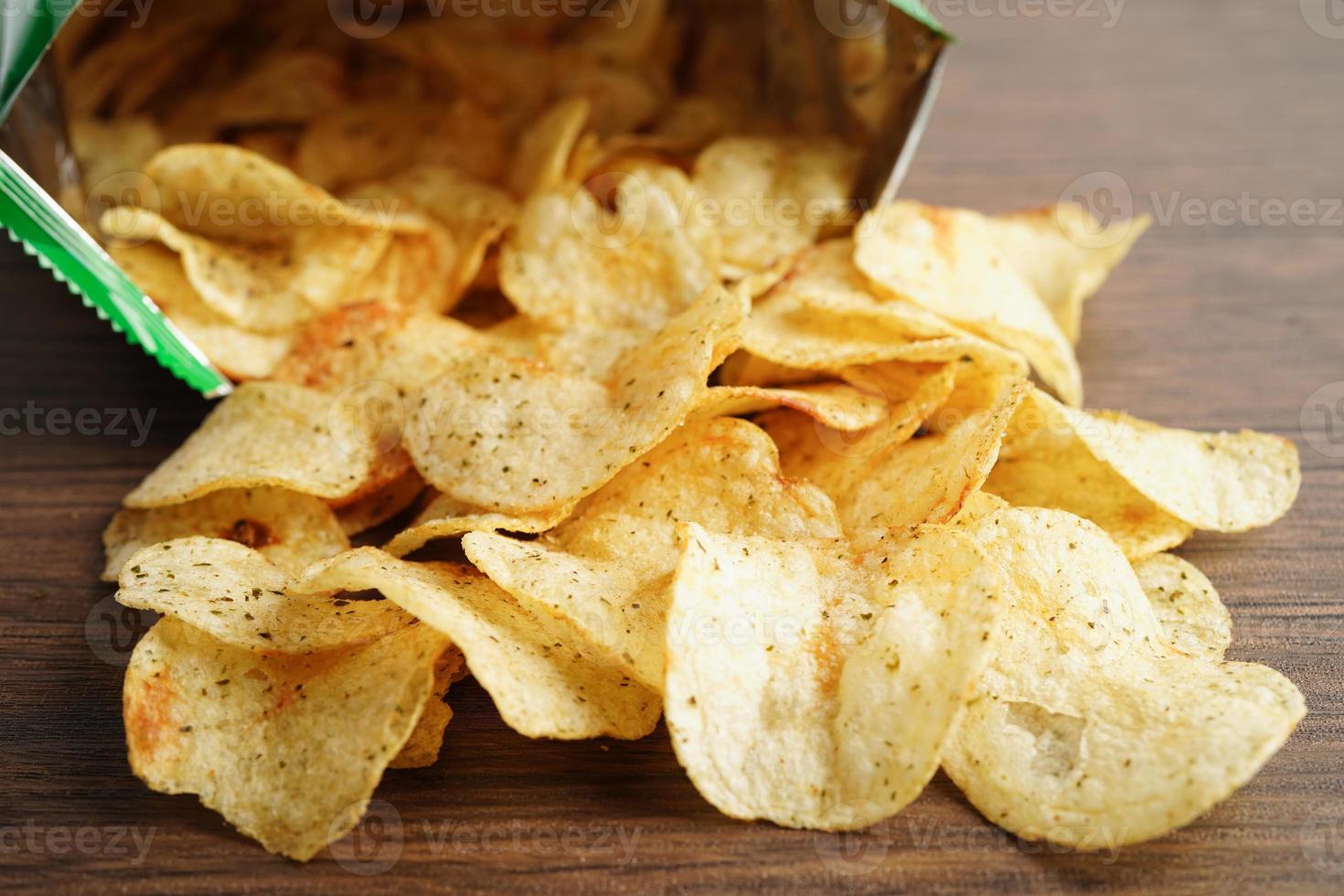 papas fritas en bolsa abierta, delicioso condimento de barbacoa picante para crips, refrigerio frito en rodajas finas comida rápida en bolsa abierta. foto