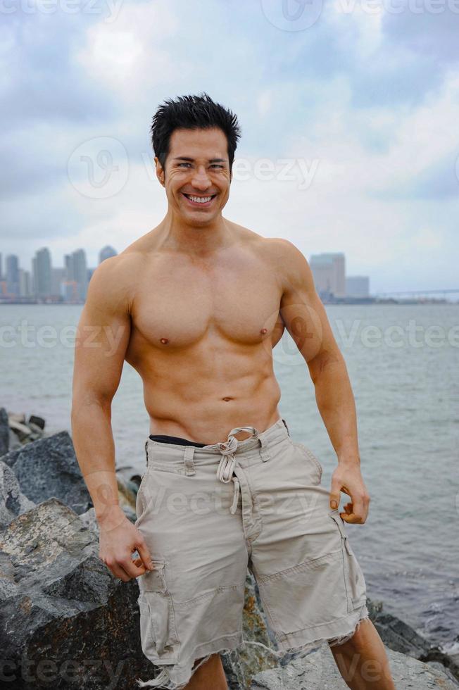 Athletic male model poses shirtless by the entrance to the San Diego Harbor, California. photo