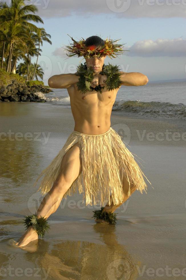 This Hawaiian Hula Dancer hits a strength pose and showing off his muscular leg on the beach in Maui, Hawaii photo