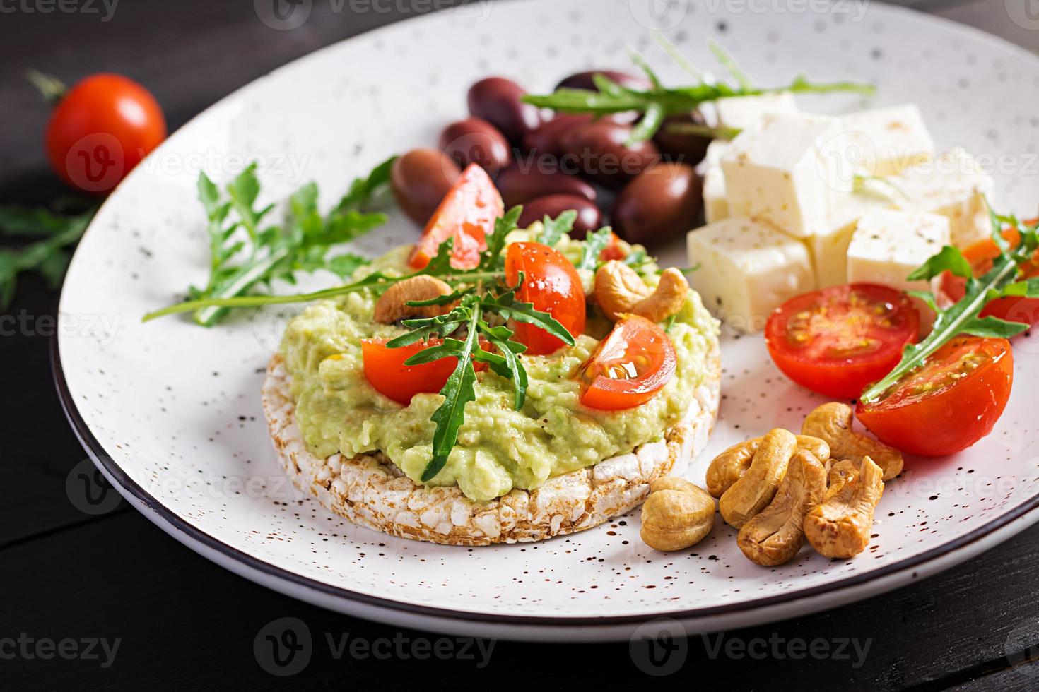 Healthy avocado toasts for breakfast or lunch,  guacamole avocado, kalamata olives, tomatoes, cashew nuts and  feta cheese. Vegetarian sandwiches photo