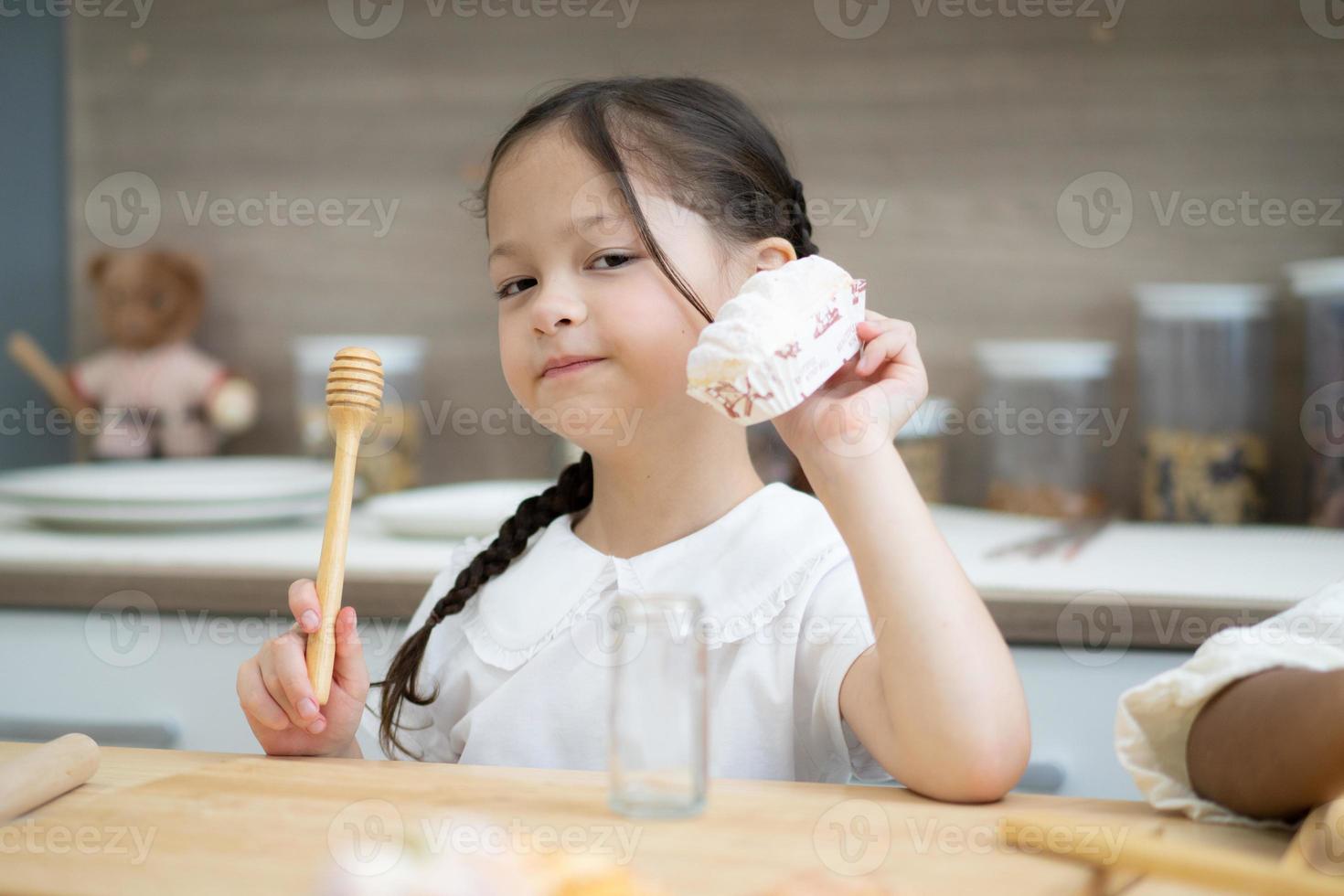 Happy little kids siblings cooking together, standing at wooden countertop in modern kitchen, preparing homemade photo