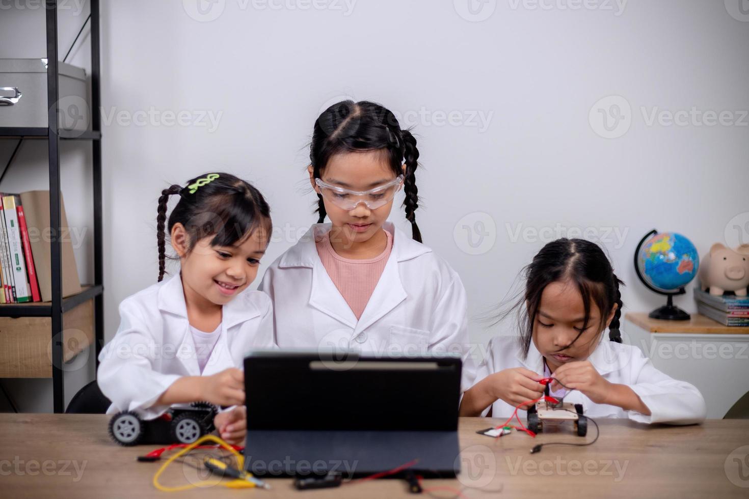 los estudiantes asiáticos aprenden en casa codificando automóviles robot y cables de placas electrónicas en tallo, vapor, ingeniería matemática, ciencia, tecnología, código informático en robótica para conceptos infantiles. foto