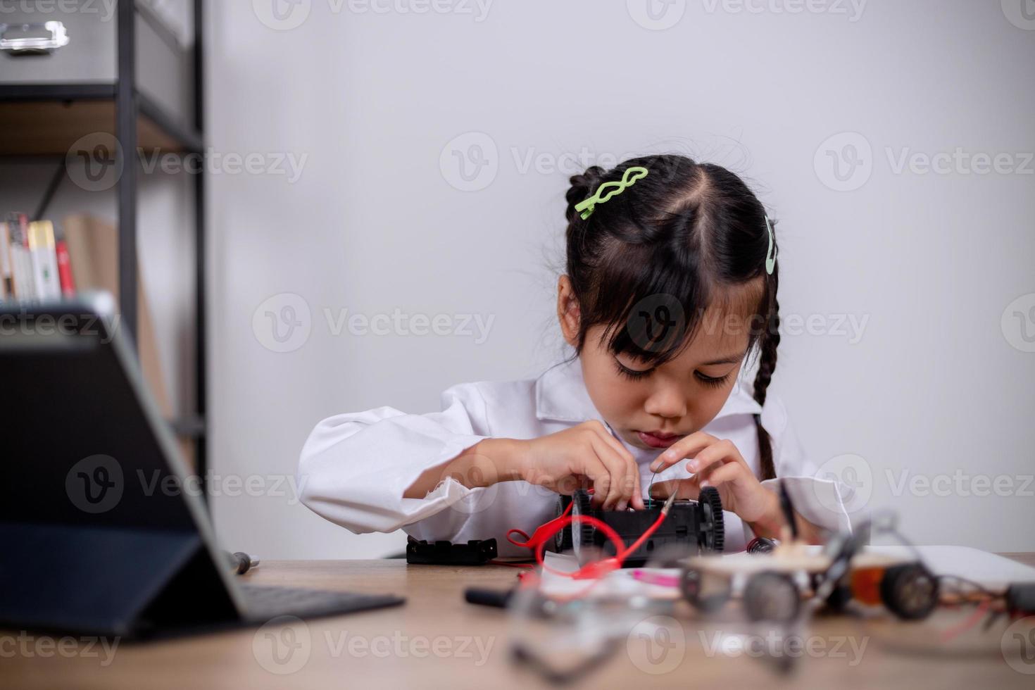 Asian students learn at home by coding robot cars and electronic board cables in STEM, STEAM, mathematics engineering science technology computer code in robotics for kids' concepts. photo