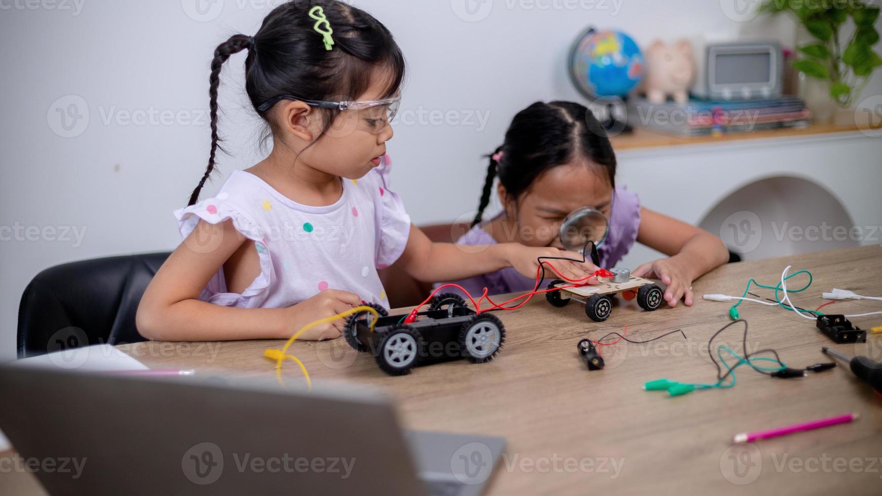 Asian students learn at home by coding robot cars and electronic board cables in STEM, STEAM, mathematics engineering science technology computer code in robotics for kids' concepts. photo
