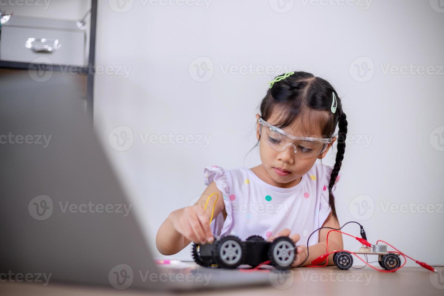 Asian students learn at home by coding robot cars and electronic board cables in STEM, STEAM, mathematics engineering science technology computer code in robotics for kids' concepts. photo