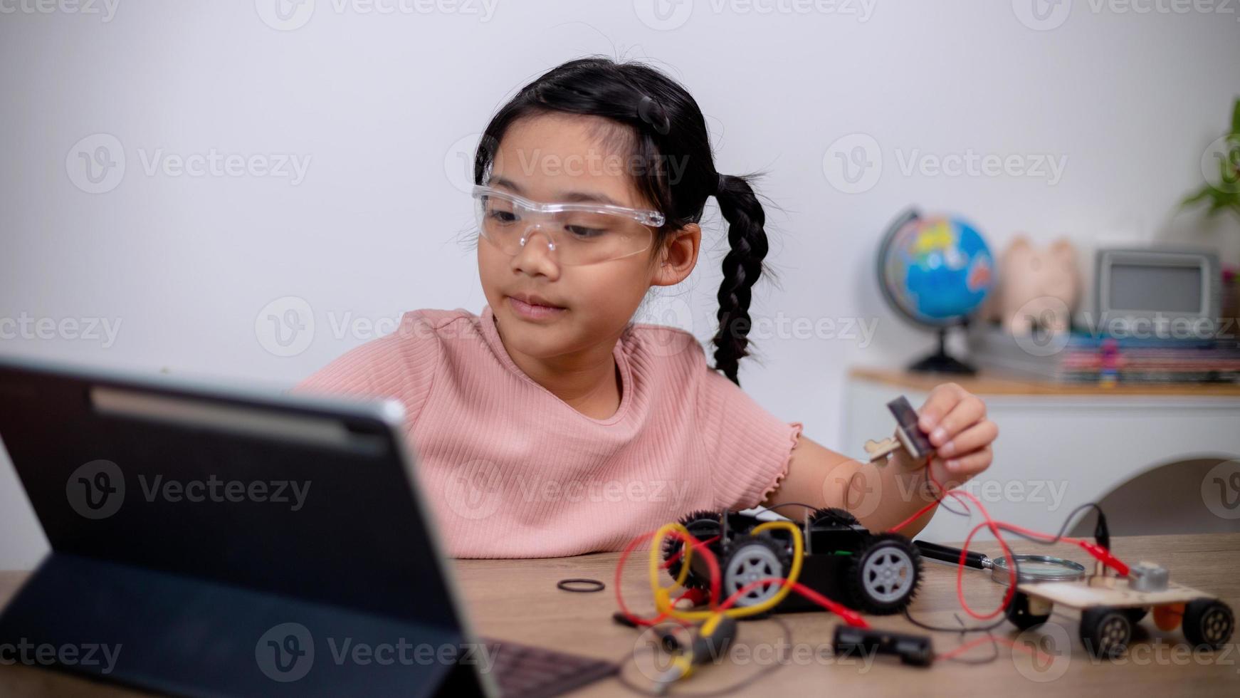 Asian students learn at home by coding robot cars and electronic board cables in STEM, STEAM, mathematics engineering science technology computer code in robotics for kids' concepts. photo