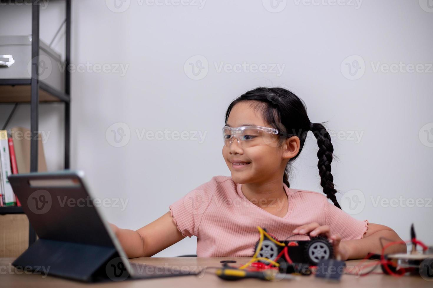 Asian students learn at home by coding robot cars and electronic board cables in STEM, STEAM, mathematics engineering science technology computer code in robotics for kids' concepts. photo