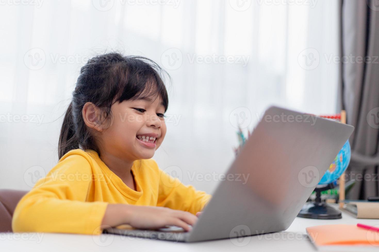 First day at school. Asian little girl using a laptop computer, studying through online e-learning system. photo