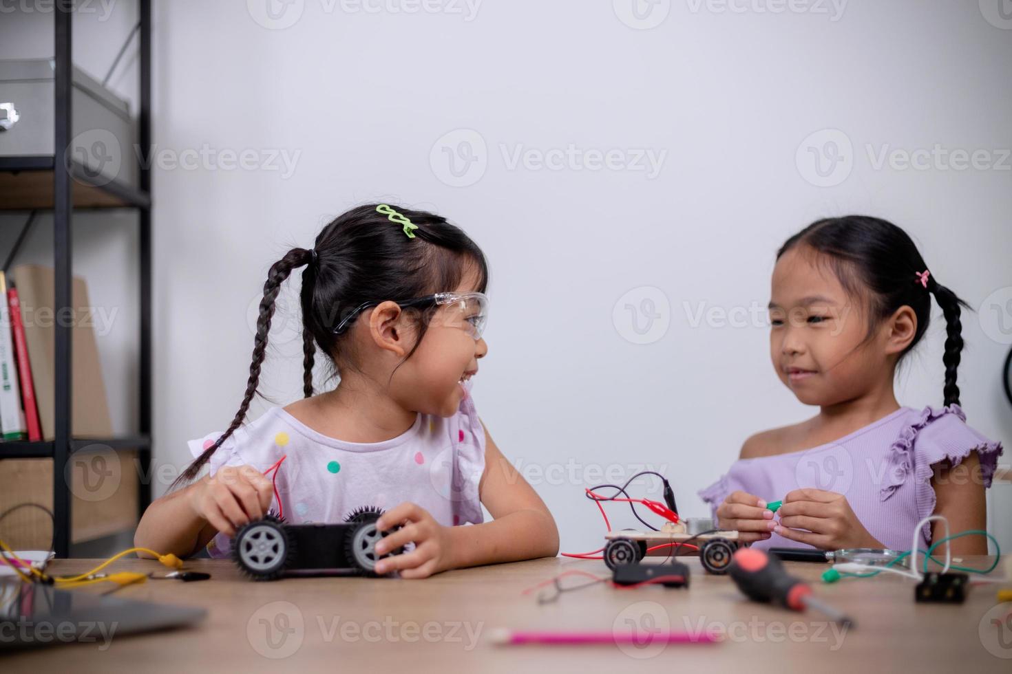 Asian students learn at home by coding robot cars and electronic board cables in STEM, STEAM, mathematics engineering science technology computer code in robotics for kids' concepts. photo