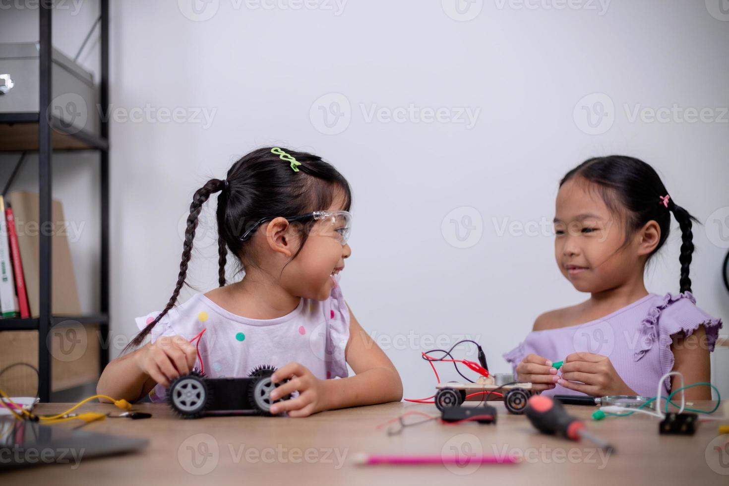 los estudiantes asiáticos aprenden en casa codificando automóviles robot y cables de placas electrónicas en tallo, vapor, ingeniería matemática, ciencia, tecnología, código informático en robótica para conceptos infantiles. foto