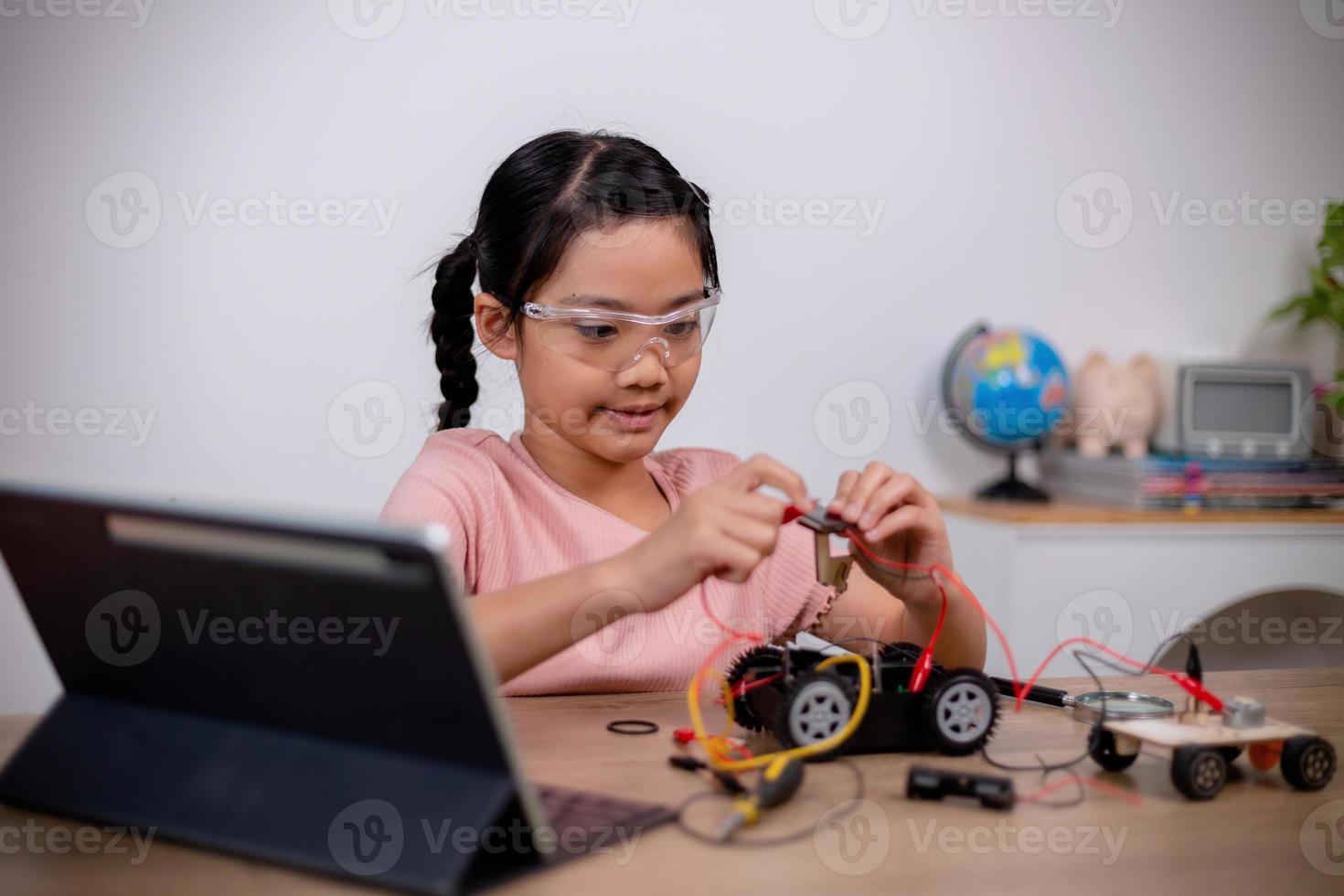 Asian students learn at home by coding robot cars and electronic board cables in STEM, STEAM, mathematics engineering science technology computer code in robotics for kids' concepts. photo