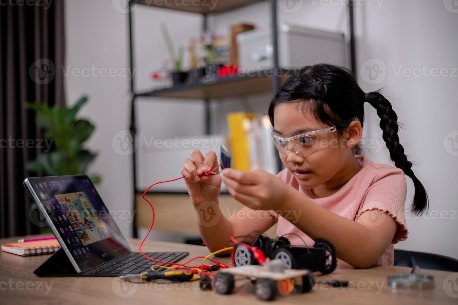 Asian students learn at home by coding robot cars and electronic board cables in STEM, STEAM, mathematics engineering science technology computer code in robotics for kids' concepts. photo
