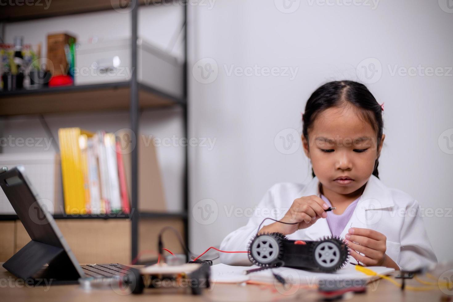 Asian students learn at home by coding robot cars and electronic board cables in STEM, STEAM, mathematics engineering science technology computer code in robotics for kids' concepts. photo