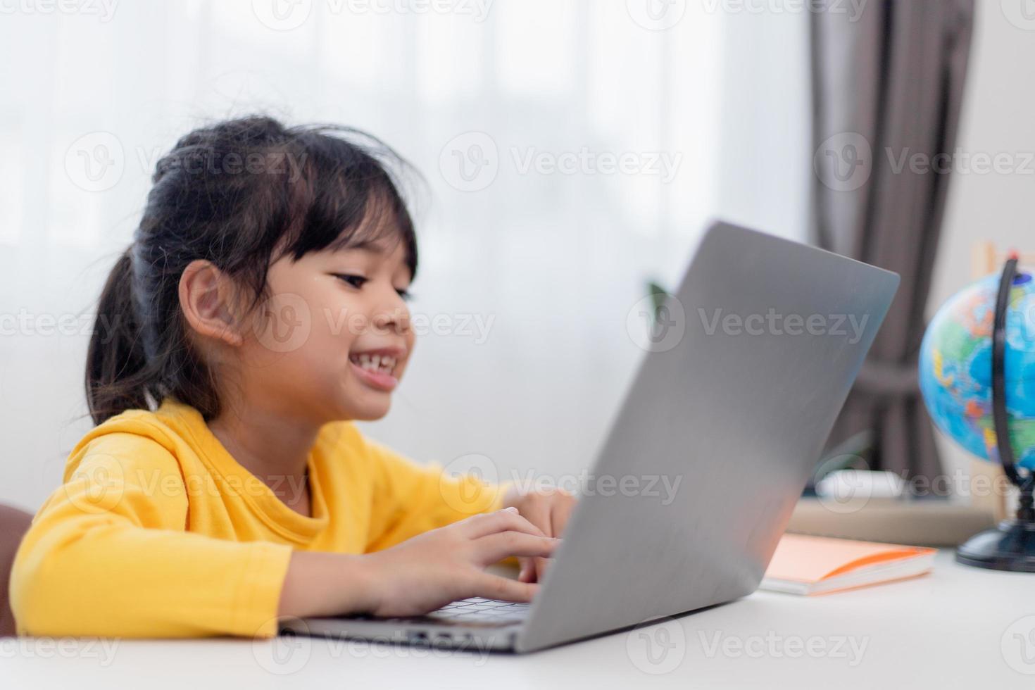 First day at school. Asian little girl using a laptop computer, studying through online e-learning system. photo