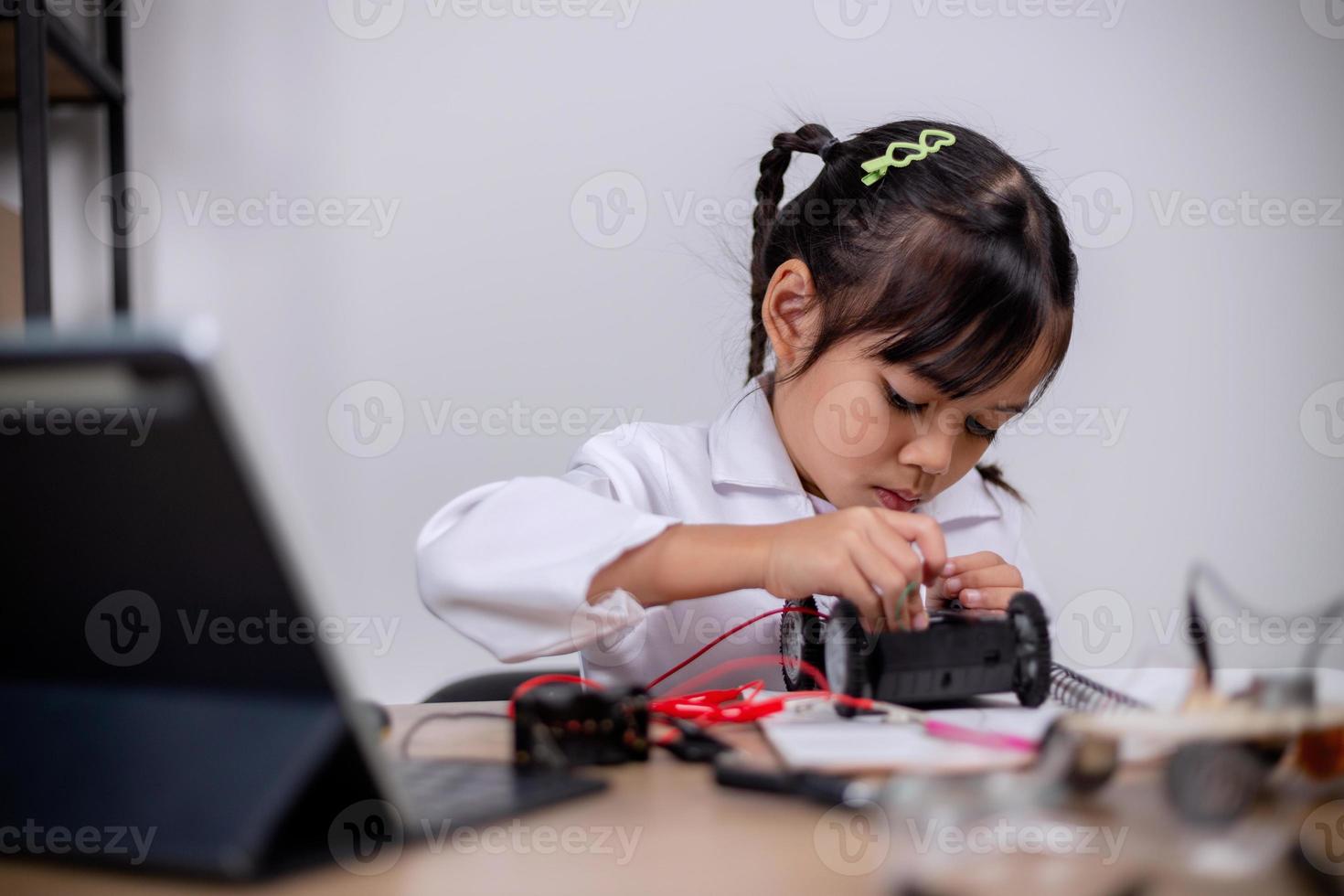 los estudiantes asiáticos aprenden en casa codificando automóviles robot y cables de placas electrónicas en tallo, vapor, ingeniería matemática, ciencia, tecnología, código informático en robótica para conceptos infantiles. foto