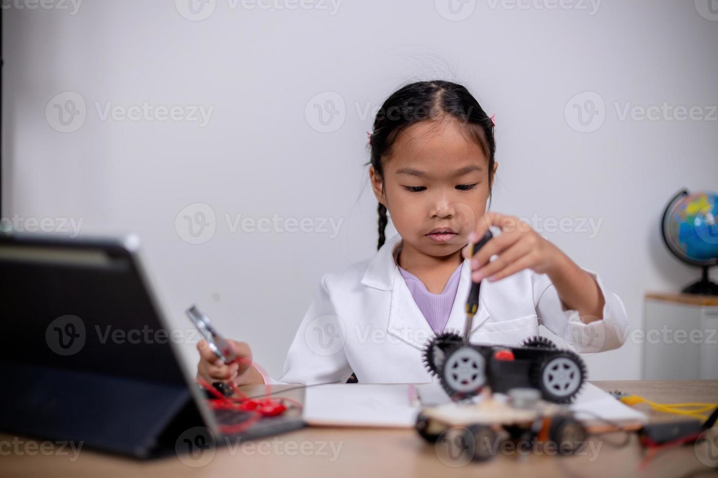 Asian students learn at home by coding robot cars and electronic board cables in STEM, STEAM, mathematics engineering science technology computer code in robotics for kids' concepts. photo