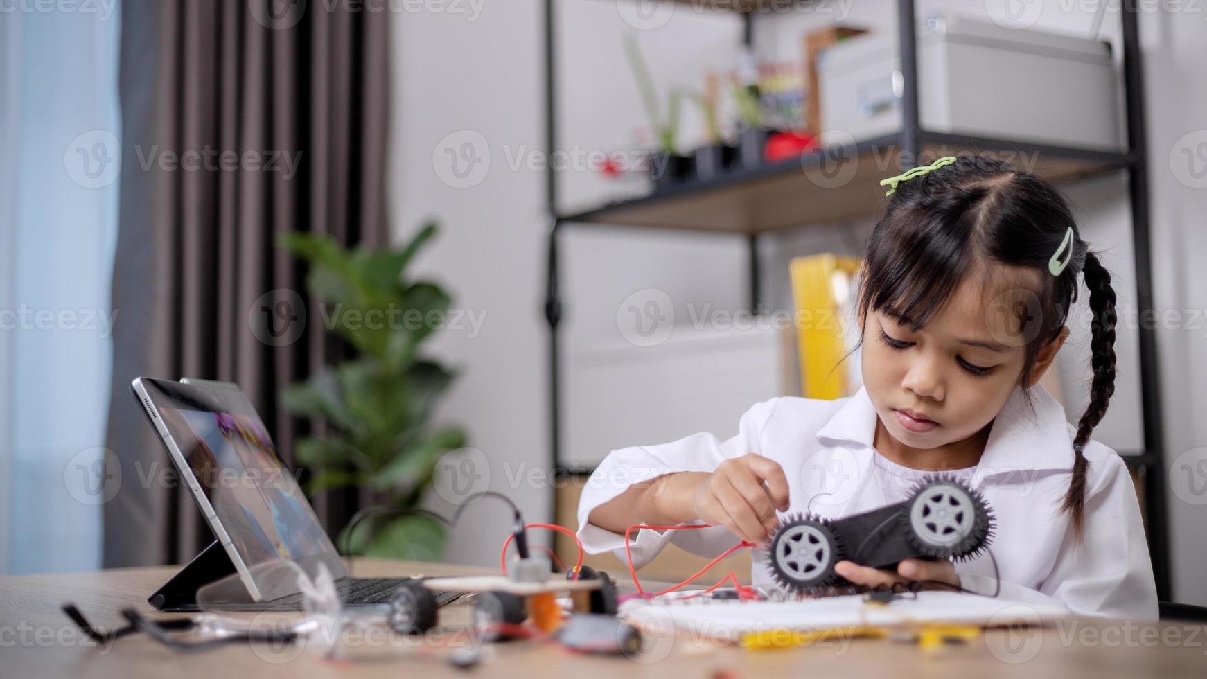 Asian students learn at home by coding robot cars and electronic board cables in STEM, STEAM, mathematics engineering science technology computer code in robotics for kids' concepts. photo