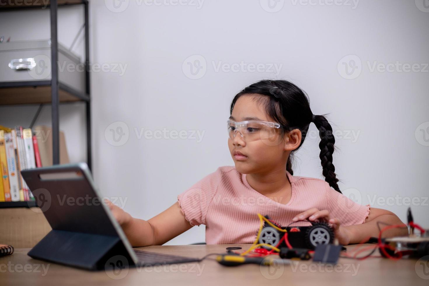 Asian students learn at home by coding robot cars and electronic board cables in STEM, STEAM, mathematics engineering science technology computer code in robotics for kids' concepts. photo