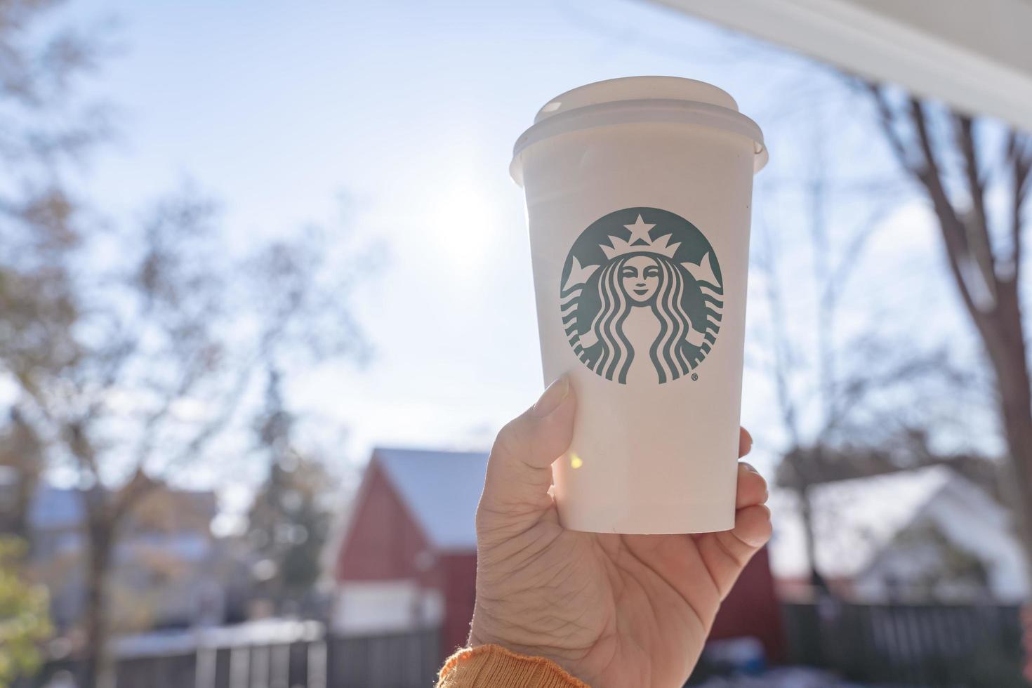 Marinette,WI,USA - Nov14, 2023- Cups of Starbucks Hot Coffee put on white snow in winter garden, fresh and hot beverage take away concept.Starbucks Cafe Coffee Shop. photo