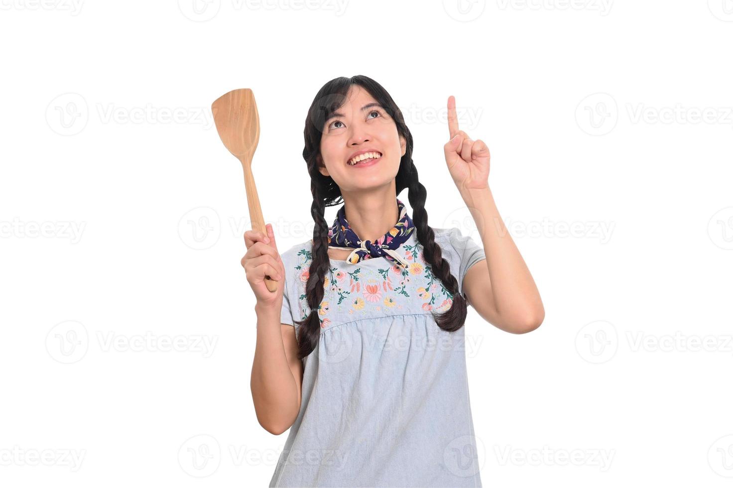 Portrait of beautiful young asian woman smile in denim dress with spatula on white background photo
