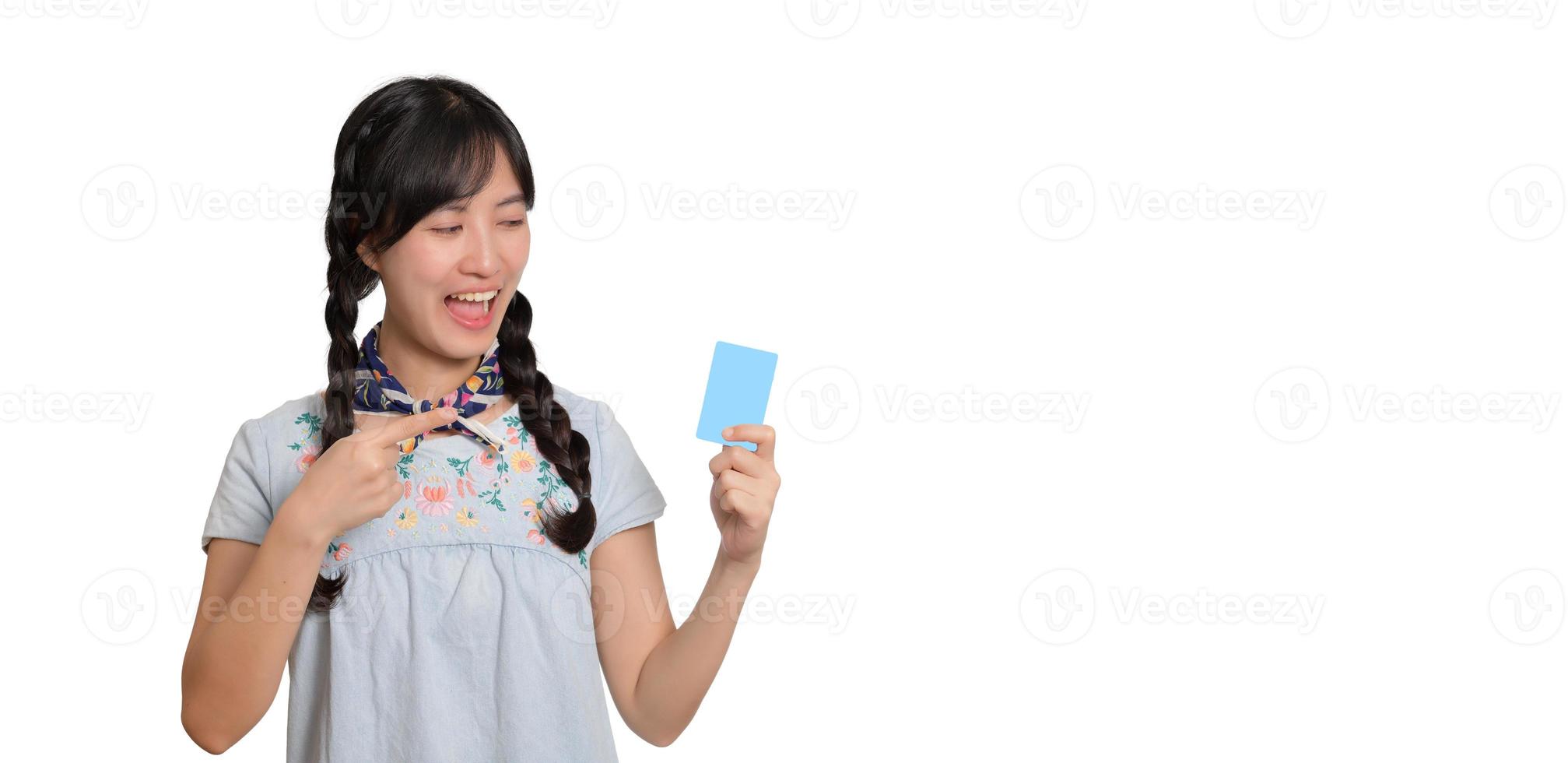 Portrait of beautiful happy young asian woman in denim dress holding credit card on white background photo