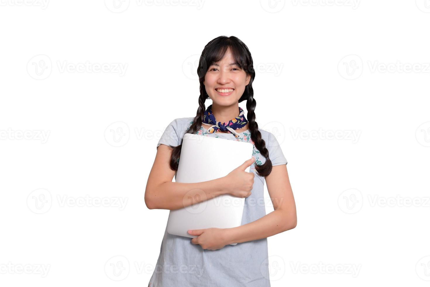 retrato de una hermosa y feliz joven mujer asiática independiente vestida de mezclilla usando un trabajo portátil con éxito en el fondo blanco foto