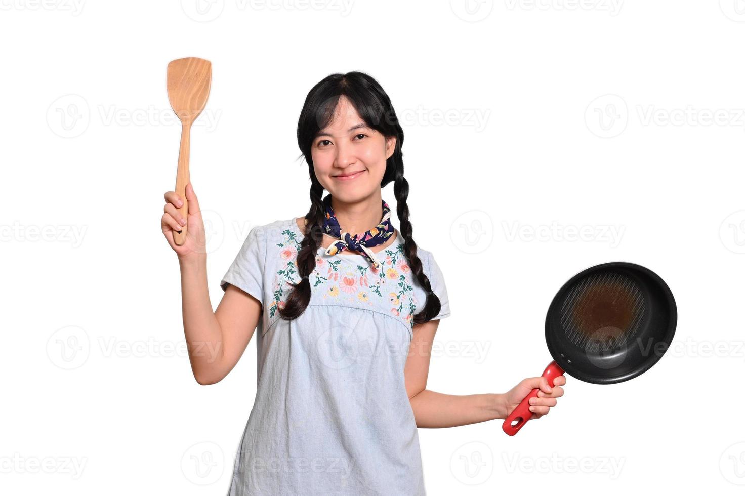 Portrait of beautiful young asian woman wear denim dress with black pan and spatula on white isolated background photo