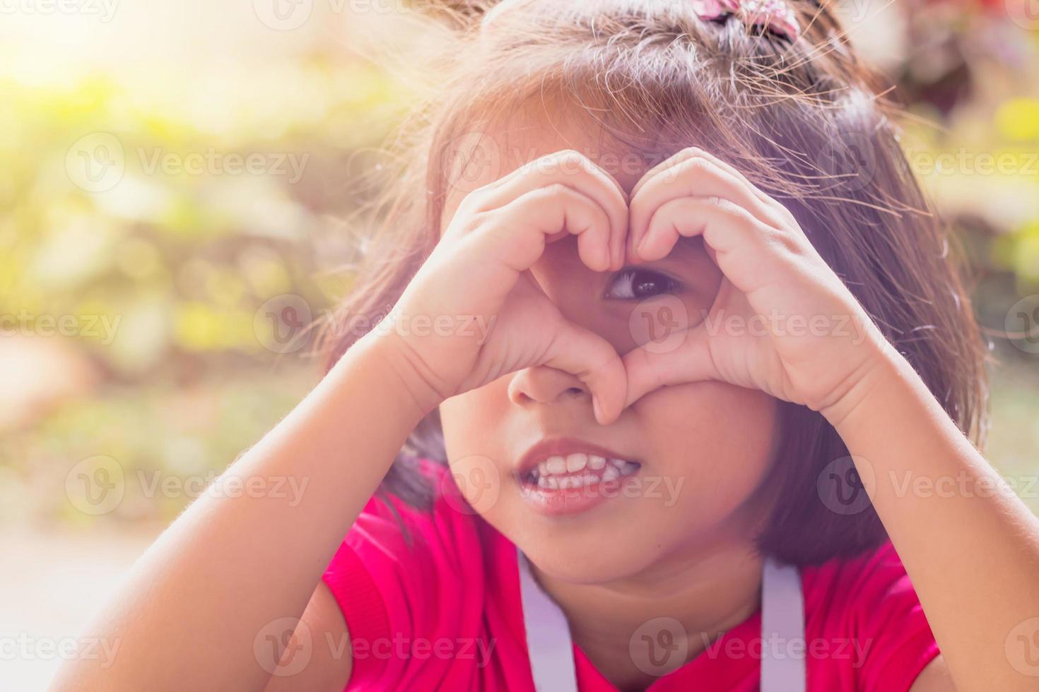 Asian kid make hands gesture in the heart shape of love. for Valentine's Day celebrated concept. photo