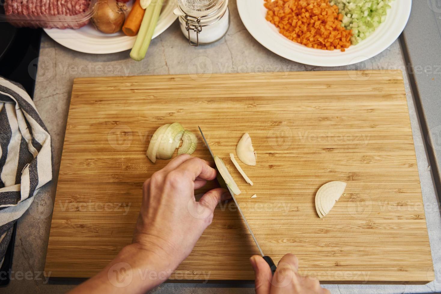 Woman chopping onion in kitchen, close up photo