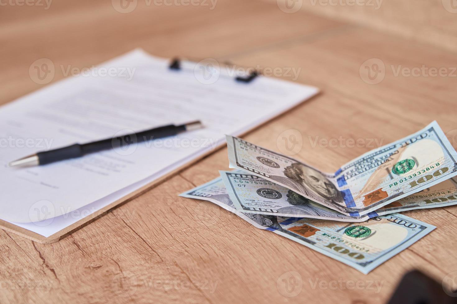 Document, pen and dollar bills on table, close up photo