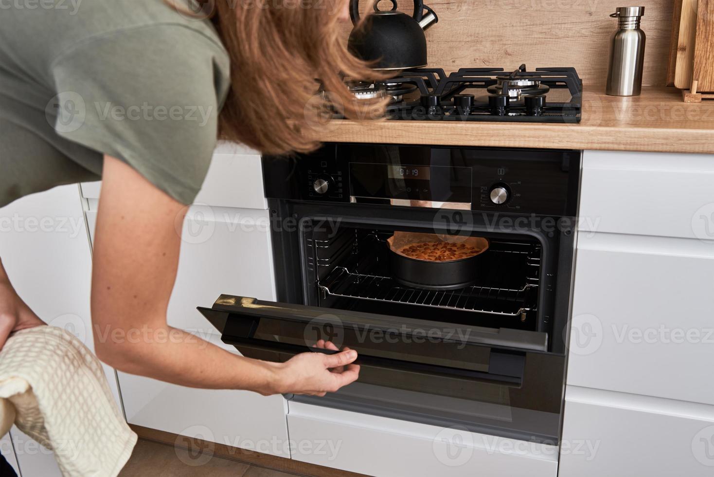 mujer cocinando pastel en horno eléctrico foto