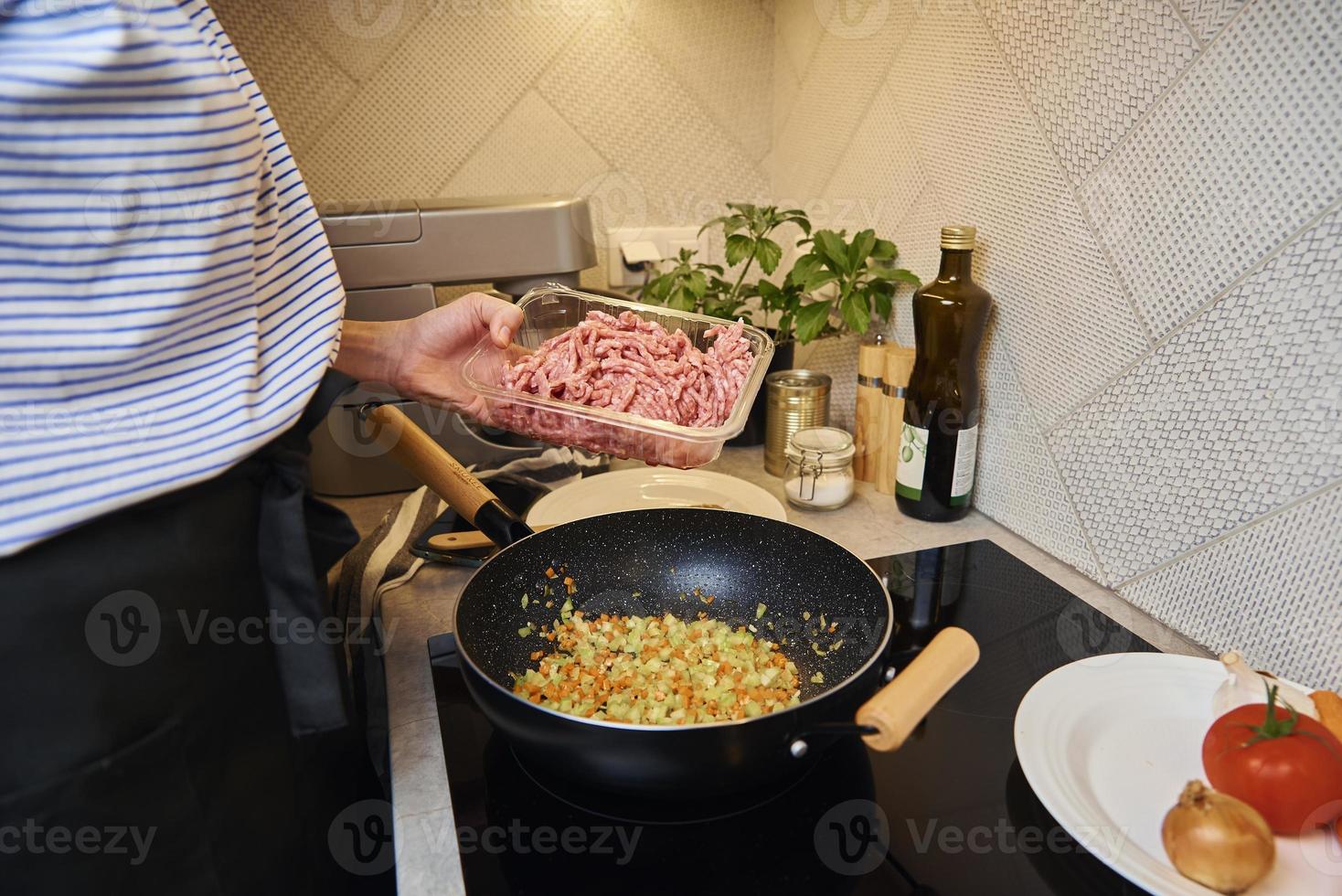 Woman cooking sauce bolognese in kitchen photo