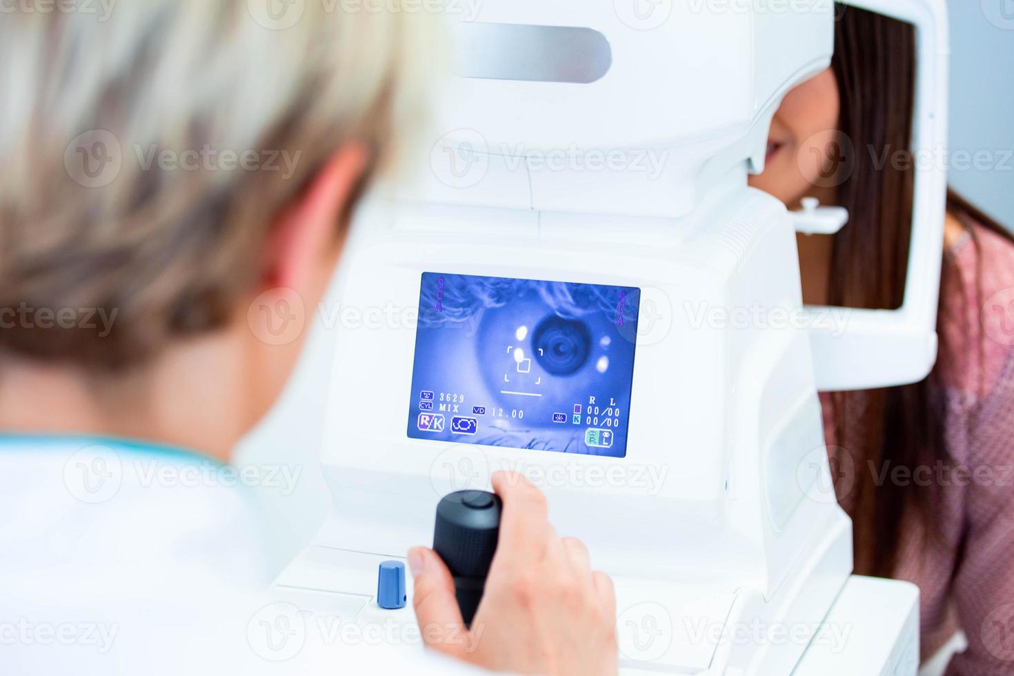 Female doctor ophthalmologist is checking the eye vision of attractive young woman in modern clinic. Doctor and patient in ophthalmology clinic. photo