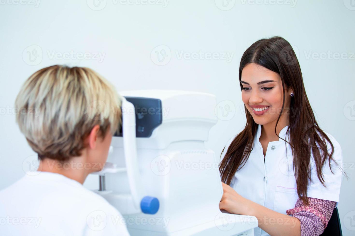 Female doctor ophthalmologist is checking the eye vision of attractive young woman in modern clinic. Doctor and patient in ophthalmology clinic. photo