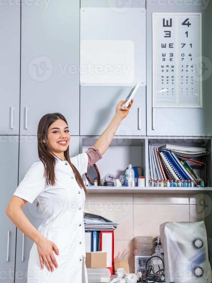 Young ophthalmologist near eye chart indoors, ophthalmologist doctor performing eye test photo