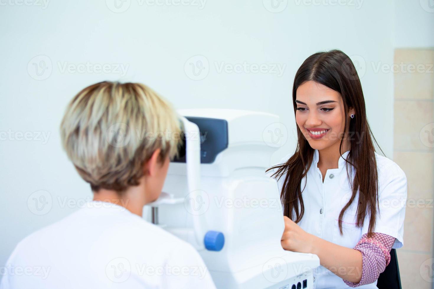 Female doctor ophthalmologist is checking the eye vision of attractive young woman in modern clinic. Doctor and patient in ophthalmology clinic. photo