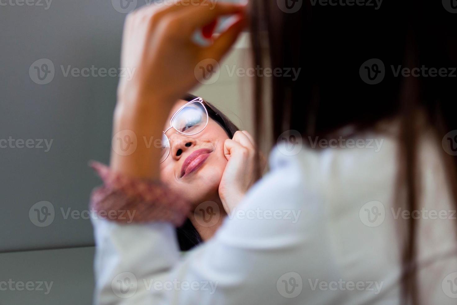 Young girl trying on eyeglasses in front of mirror. Helping to improve vision, saving eye health photo