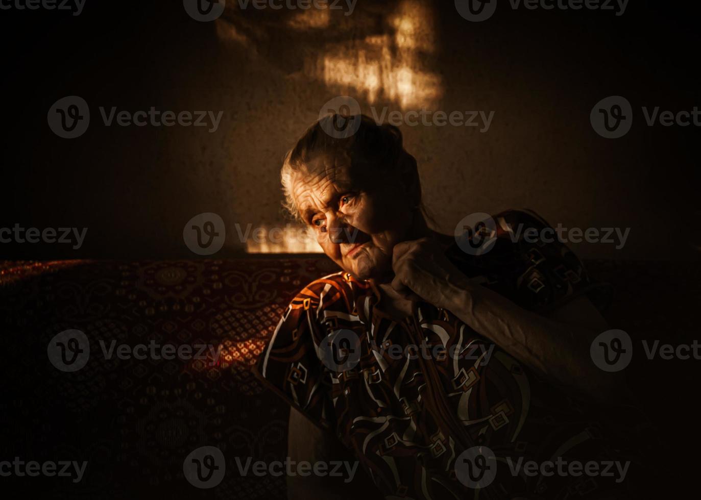 very old and tired wrinkled woman sitting on a sofa photo