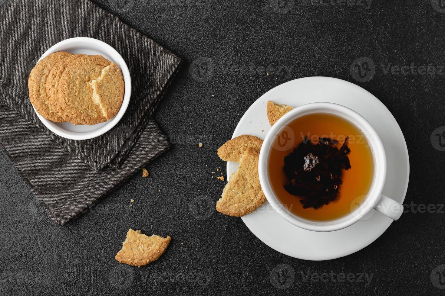 Cup of tea with cookies on black background. photo