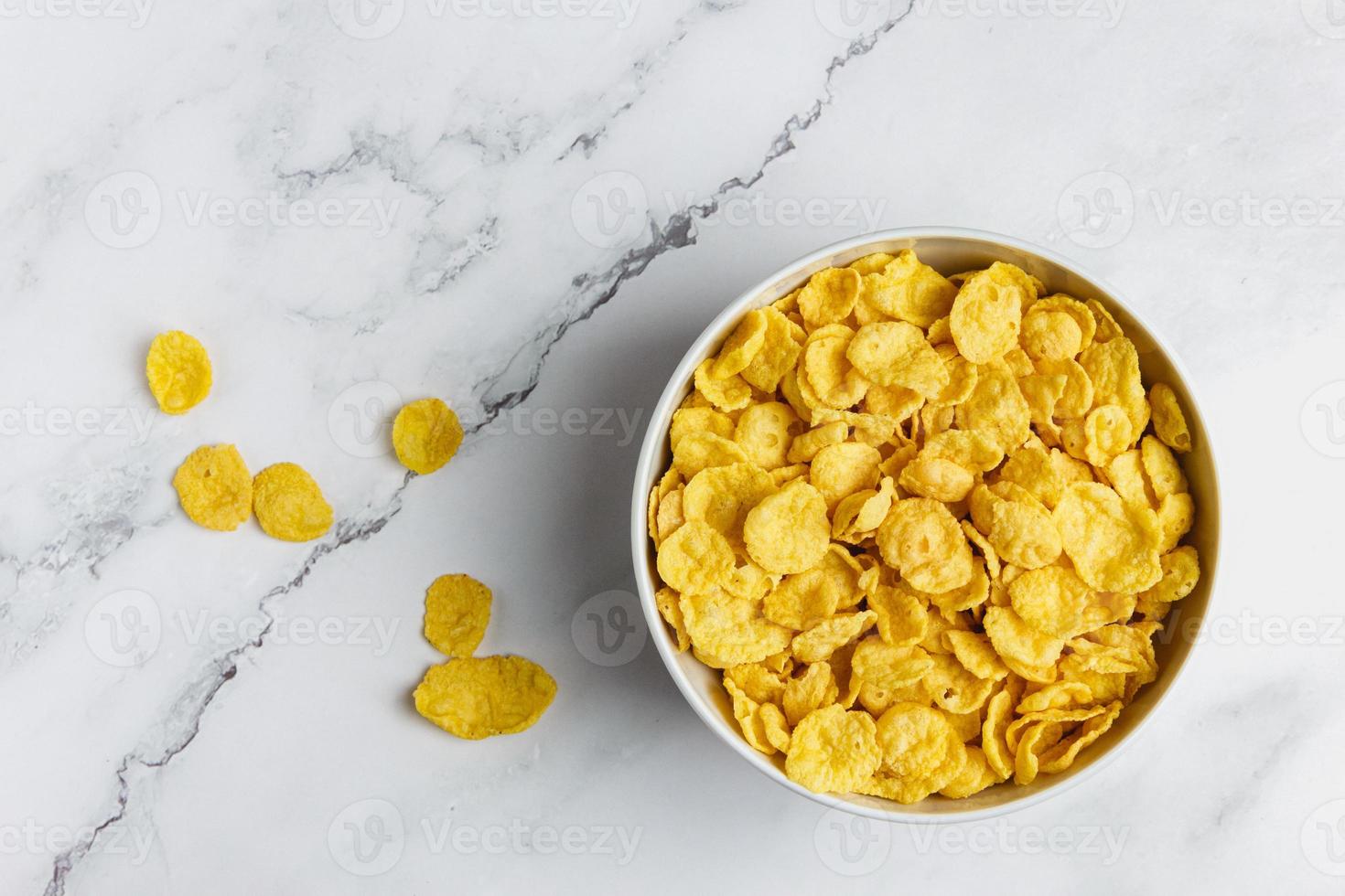 Corn flakes in white bowl on marble table. photo