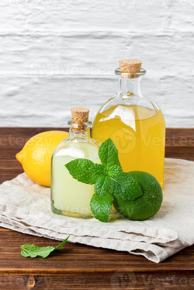 Lime and lemon syrups in a glass bottle with fruits and mint photo