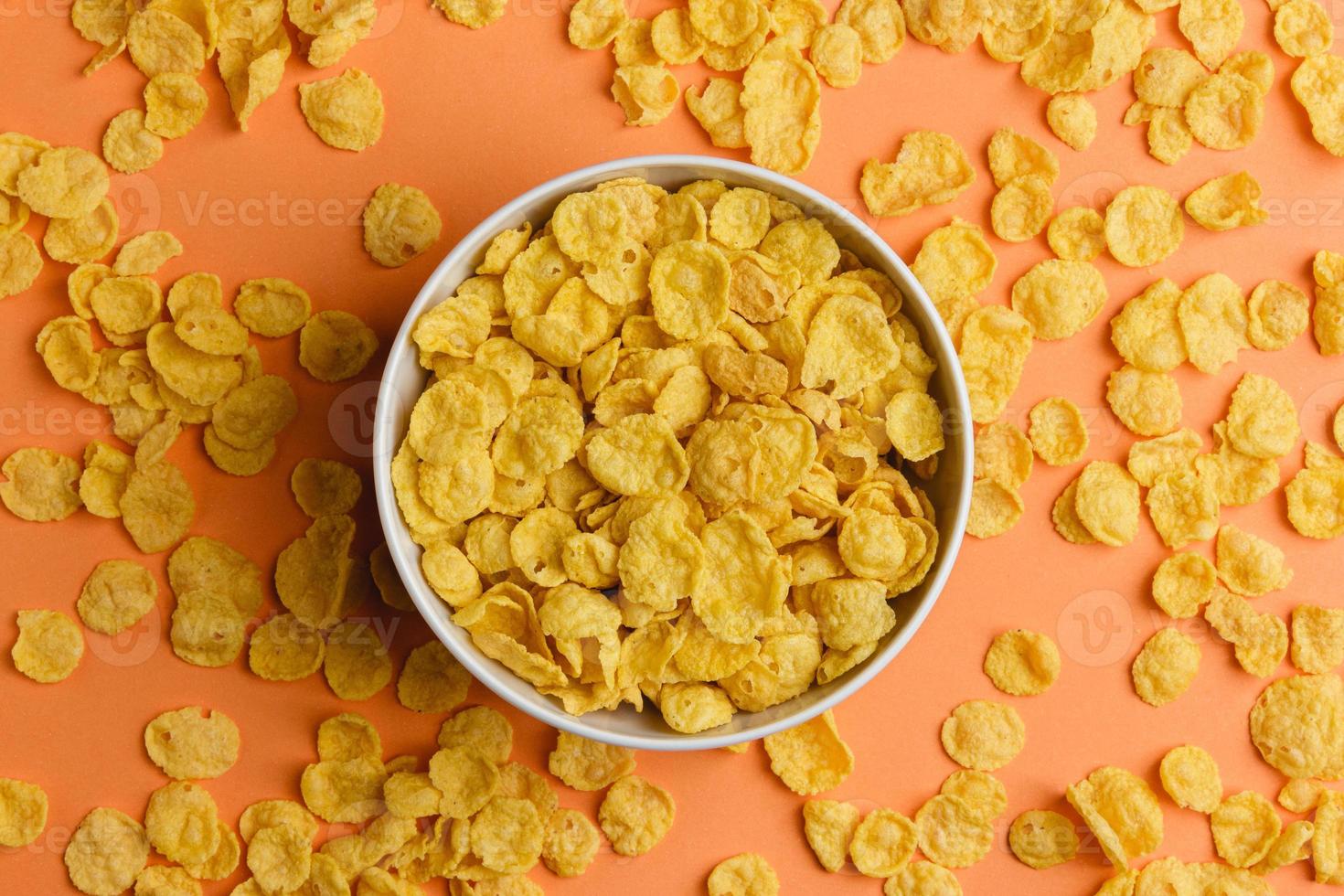 Corn flakes in white bowl on orange background. photo