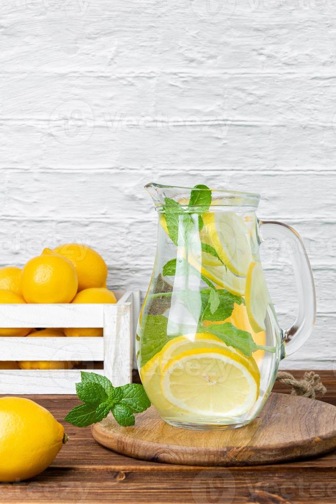 Lemonade with mint in jug and lemons in crate photo